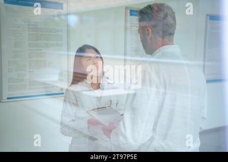 Scientists having discussion seen through glass in laboratory Stock Photo