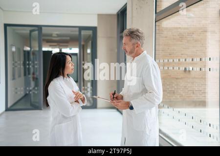 Scientists having discussion together in laboratory corridor Stock Photo