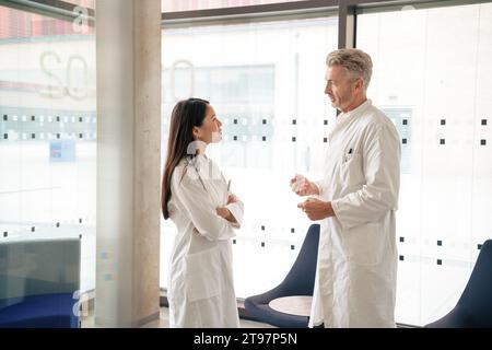 Scientists having discussion together in front of glass Stock Photo