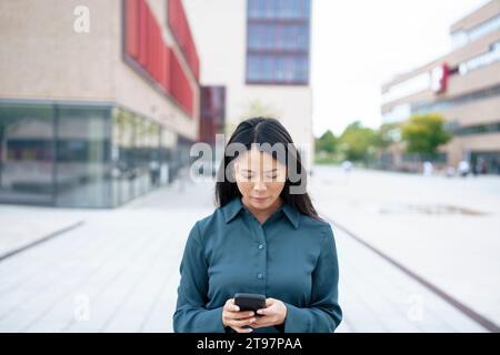 Businesswoman using mobile phone in office park Stock Photo