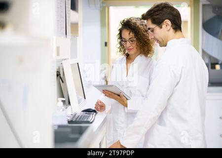Pharmacist working with colleague using tablet PC at pharmacy Stock Photo
