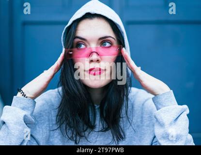 Young woman wearing pink lipstick and adjusting smart glasses Stock Photo
