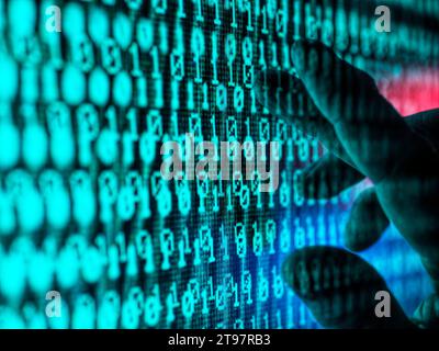 Hand of man touching screen displaying binary code Stock Photo