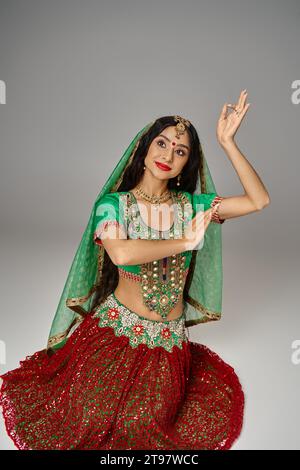 attractive indian female model with bindi dot on forehead posing on floor and gesturing with hands Stock Photo