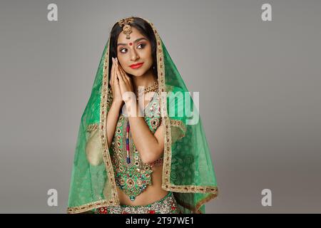 attractive indian female model in national costume with veil and bindi posing on gray backdrop Stock Photo