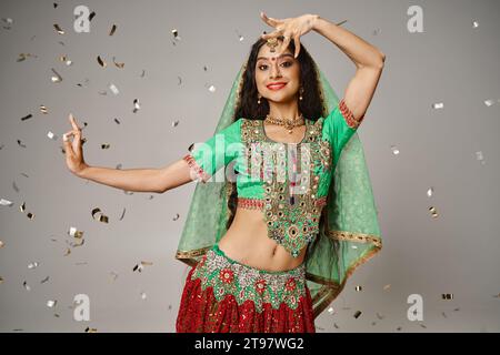 attractive indian female model in traditional clothes posing in motion surrounded by confetti Stock Photo