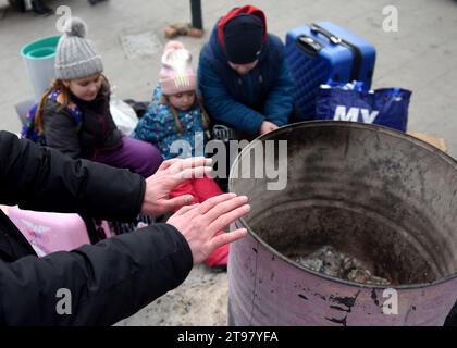Lviv, Ukraine - March 8, 2022: Refugees warm up around a bonfire outside the Lviv train station in western Ukraine. Stock Photo