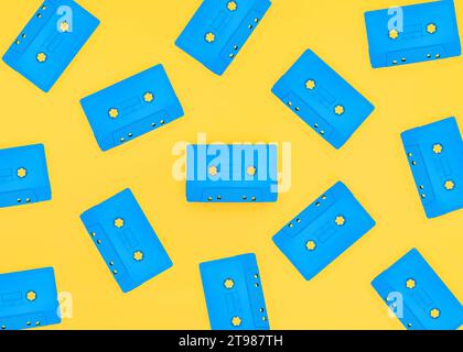 Retro blue cassette tapes scattered on a bright yellow background. Studio shot with copy space. Stock Photo
