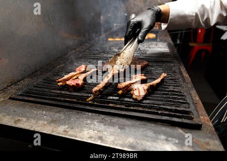 Appetizing juicy ribeye steaks and fillets laid out on the grill over a burning flame during grilling. The chef prepares tomahawk steaks on the grill. Stock Photo