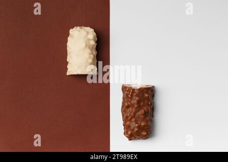 White and milk chocolate on contrasting backgrounds. Two halves of a chocolate bar with crispy wafers. Conceptual representation of two opposites Stock Photo