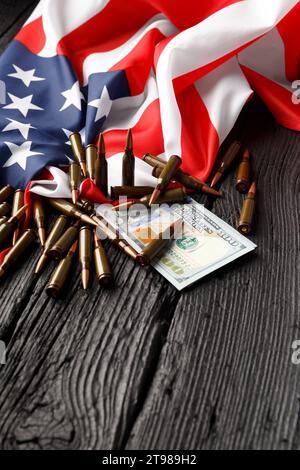 American flag, dollars, bullets, shells, cartridges, ammunition on a black wooden background. The concept of lend-lease, army, arms sales. Military Stock Photo