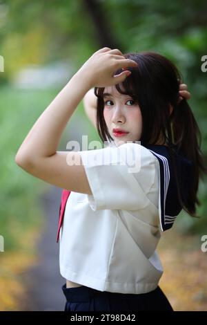 Japanese high school student tied her hair up in park with tree background Stock Photo