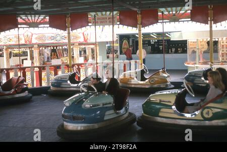 1968, historical, summer and a mother and son having fun together in a dodgem car at a fairground, England, UK. Also known as bumper cars, as these electric powered small cars with rubber bumpers all round are designed to 'bump' into the other such cars and are a  traditonal amusement ride at a British funfair. Stock Photo
