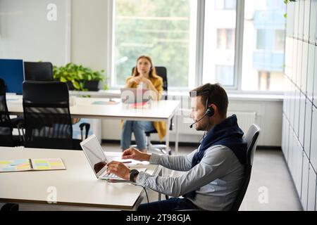 Managers with laptops at their workplaces communicate using a headset Stock Photo