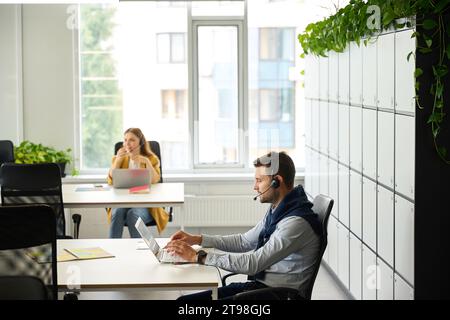 Young managers with laptops at their workplaces communicate using headset Stock Photo
