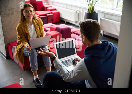 Female and male sit with laptops in a coworking space Stock Photo