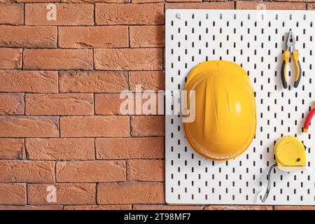 Pegboard with builder's tools on brick wall in workshop Stock Photo