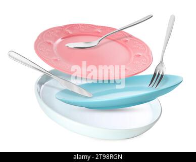 Clean plates, spoon, knife and fork falling on white background Stock Photo