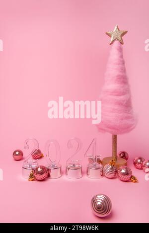 Isolated bright pink background fluffy creative Christmas tree made of wool, transparent numbers 2024 with shiny balls. New Year holiday card. Templat Stock Photo