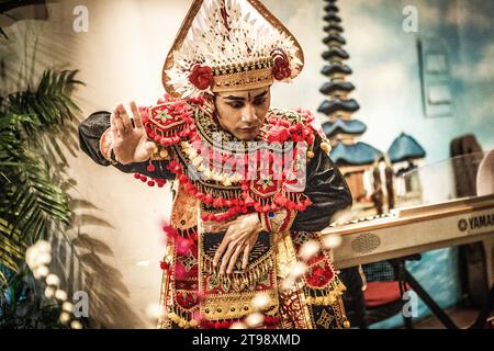 A male Balinese dancer is dancing a traditional Balinese dance wearing traditional Balinese red clothes at a cafe in Shanghai, China Stock Photo