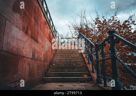 A set of stone stairs ascending the side of a red-painted brick building, leading up to a higher level Stock Photo