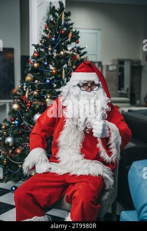 Portrait of a cheerful Santa Clause figure sitting on a couch in a cozy living room Stock Photo