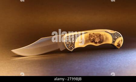 Folding hunting knife with wolves on the handle. Stock Photo