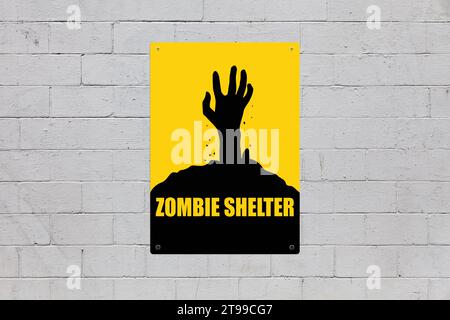 Yellow warning sign screwed to a brick wall to warn about a threat. In the middle of the panel, there is a zombie hand symbol and the message is sayin Stock Photo