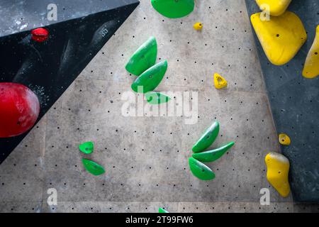 Colored bright painted climbing wall for training at bouldering gym. Multi-colored climbs walls with no people on it. Climb wall with different colorful grips in contemporary gym closeup Stock Photo