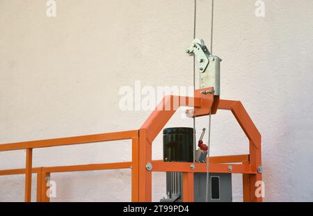 Hoist supply and safety lock as part of suspended wire rope platform for facade works on high multistorey buildings. Hoist for elevation, raising or lifting cradle platform Stock Photo
