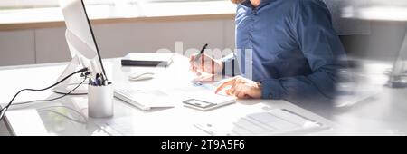 Accountant Man Using Computer Software to Calculate Invoices Stock Photo