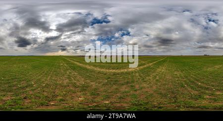 360 degree panoramic view of spherical 360 hdri panorama among green grass farming field with clouds on overcast sky in equirectangular seamless projection, use as sky dome replac