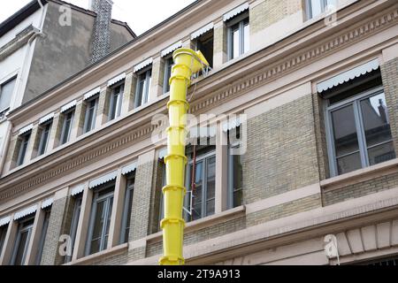 plastic slide chute yellow for rubble debris removal on building facade renewal construction site in city street Stock Photo