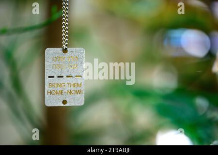 The text ' Bring Them Home - Now ' in English and Hebrew on Military style dog tags worn by many Israelis in support of the 240 Israelis abducted by H Stock Photo
