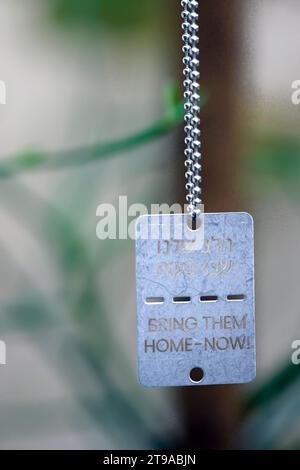 The text ' Bring Them Home - Now ' in English and Hebrew on Military style dog tags worn by many Israelis in support of the 240 Israelis abducted by H Stock Photo