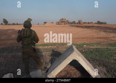 An Israeli soldier stands guard as D9 armored military bulldozers work near the border with Gaza strip amid ongoing battles between Israel and Hamas on November 23, 2023 in Southern Israel. More than a month after Hamas's Oct. 7 attacks, the country's military has continued its sustained bombardment of the Gaza Strip and launched a ground invasion to vanquish the militant group that governs the Palestinian territory Stock Photo