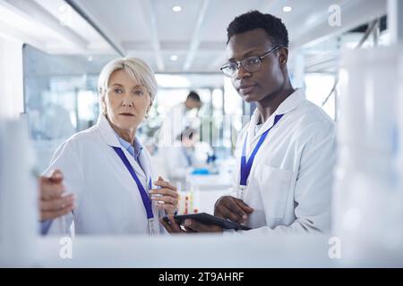 Student, medical and tablet with professor for research, disease analysis and collaboration in pharmacy. Man, senior woman and diversity for Stock Photo