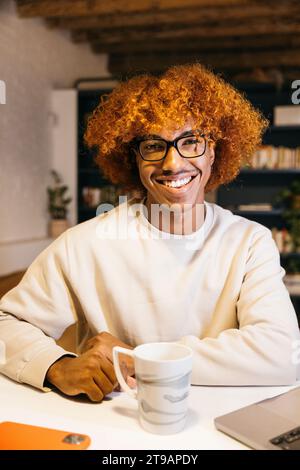 Portrait of a smiling young african american man with afro hairstyle in a living room. Happy young man in a living room. Stock Photo
