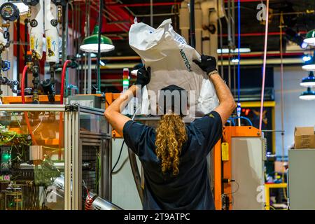 An employee at Third Man Pressing in Detroit, Michigan, United States, tips a large sack of raw granulate into a press before it is turned into vinyl records. Third Man Pressing has produced records for the independent label Third Man Records (Jack White, Ben Blackwell, Ben Swank) on Canfield Street in the Cass Corridor since 2017. Stock Photo