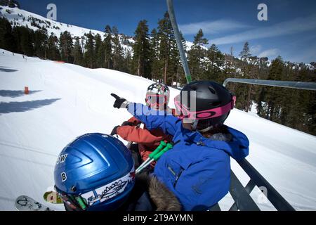 Ski instructor with two young skiers on a chairlift. Stock Photo