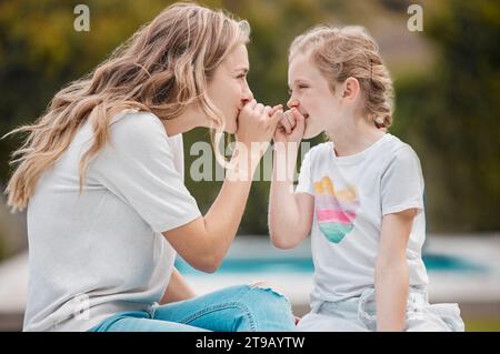 Family, secret or pinky promise with a mother and daughter outdoor in their garden or backyard together. Smile, love or happy with a young woman and Stock Photo