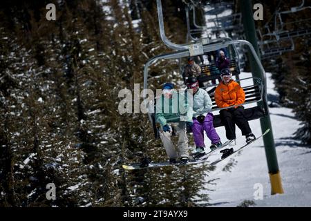 Three snowboarders having fun on a chairlift. Stock Photo
