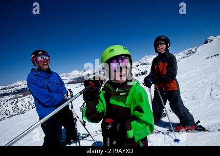Two young skiers with their ski instructor at the top of the mountain. Stock Photo