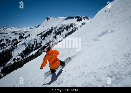 Snowboarder riding spring conditions with a nice view. Stock Photo