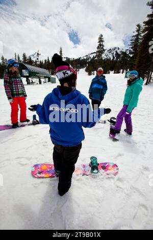 Three snowboard students listening to their snowboard instructor. Stock Photo