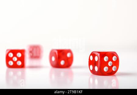 Detail of dice background for playing games of chance with several red transparent plastic dice reflected on white table and white isolated background Stock Photo