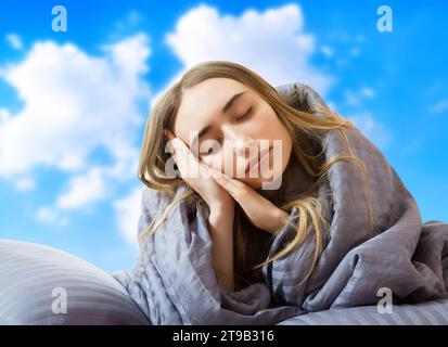 creative image: Girl woman in bed after sleep at the sky background isolated, sleep female, stay at home concept, coronavirus quarantine, wake up in t Stock Photo