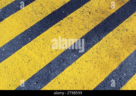 Yellow parallel hazard lines painted on asphalt road Stock Photo