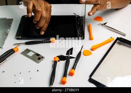 A technician carefully cleans a tabl for repair using a variety of tools Stock Photo