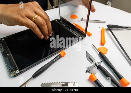 A technician carefully cleans a tablet for repair using a variety of tools Stock Photo